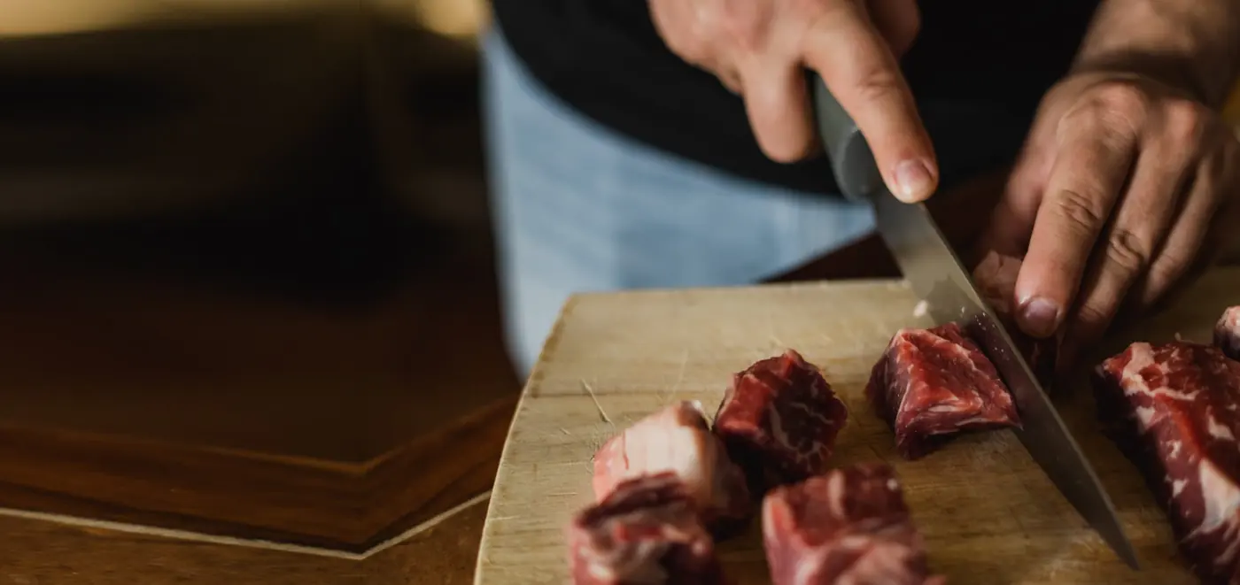 Maestro carnicero cortando carne sobre una tabla de madera